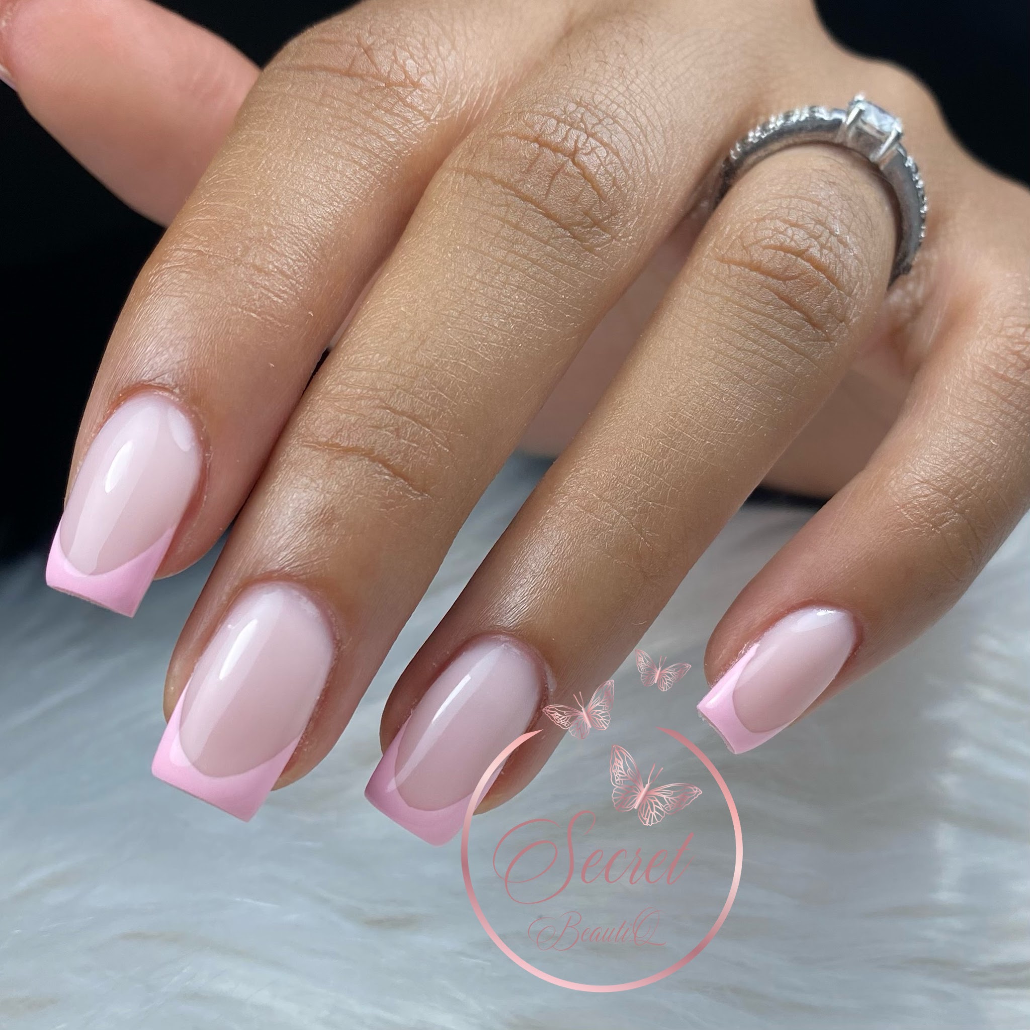 Roze French nagels op een hand met een ring
