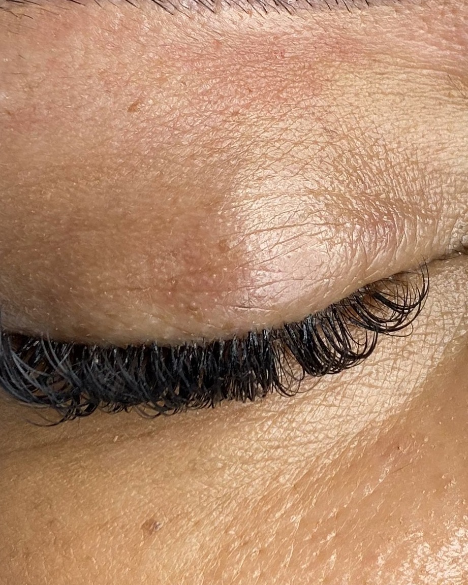 Close-up van een gesloten oog met volle wimperextensions en een gevormde wenkbrauw