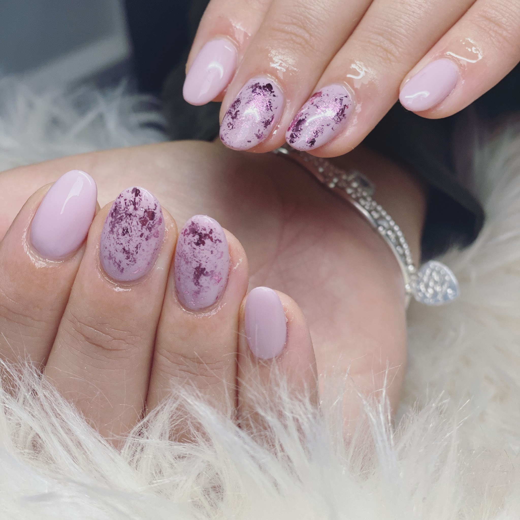 Lila nagels met paarse folie-accenten, gefotografeerd op wit bont
