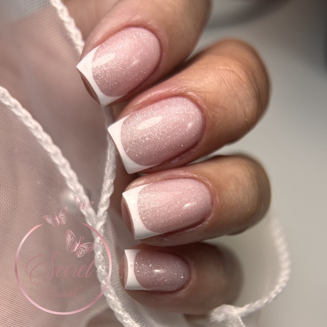Glanzende roze nagels met witte French tips op een witte stof